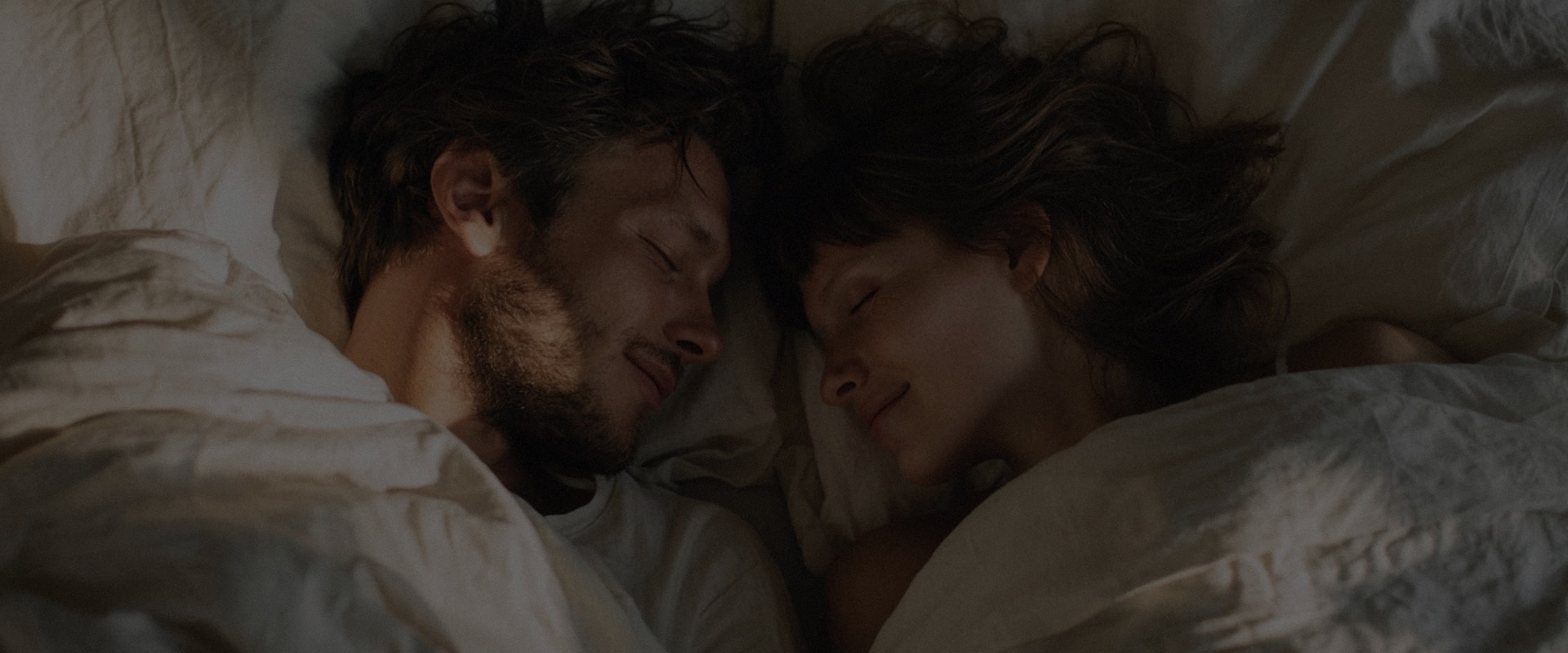Couple qui dort proche l'un de l'autre dans un lit avec deux couettes